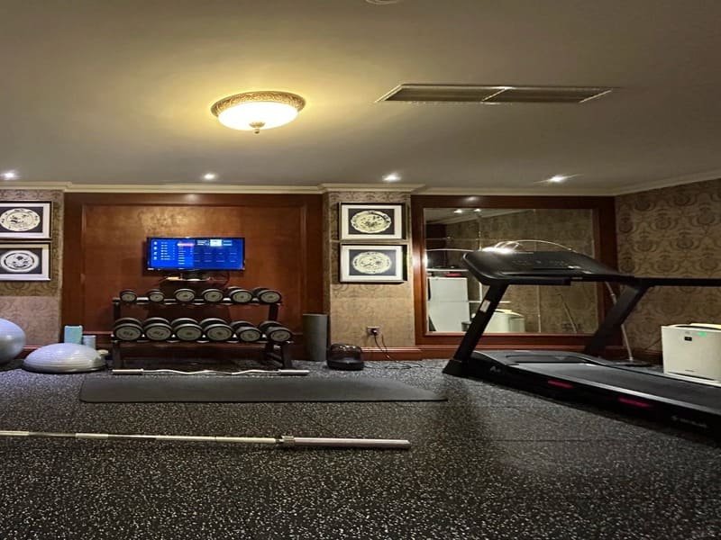 Pracownik czyszczący gumową podłogę siłowni za pomocą automatycznej szorowarki